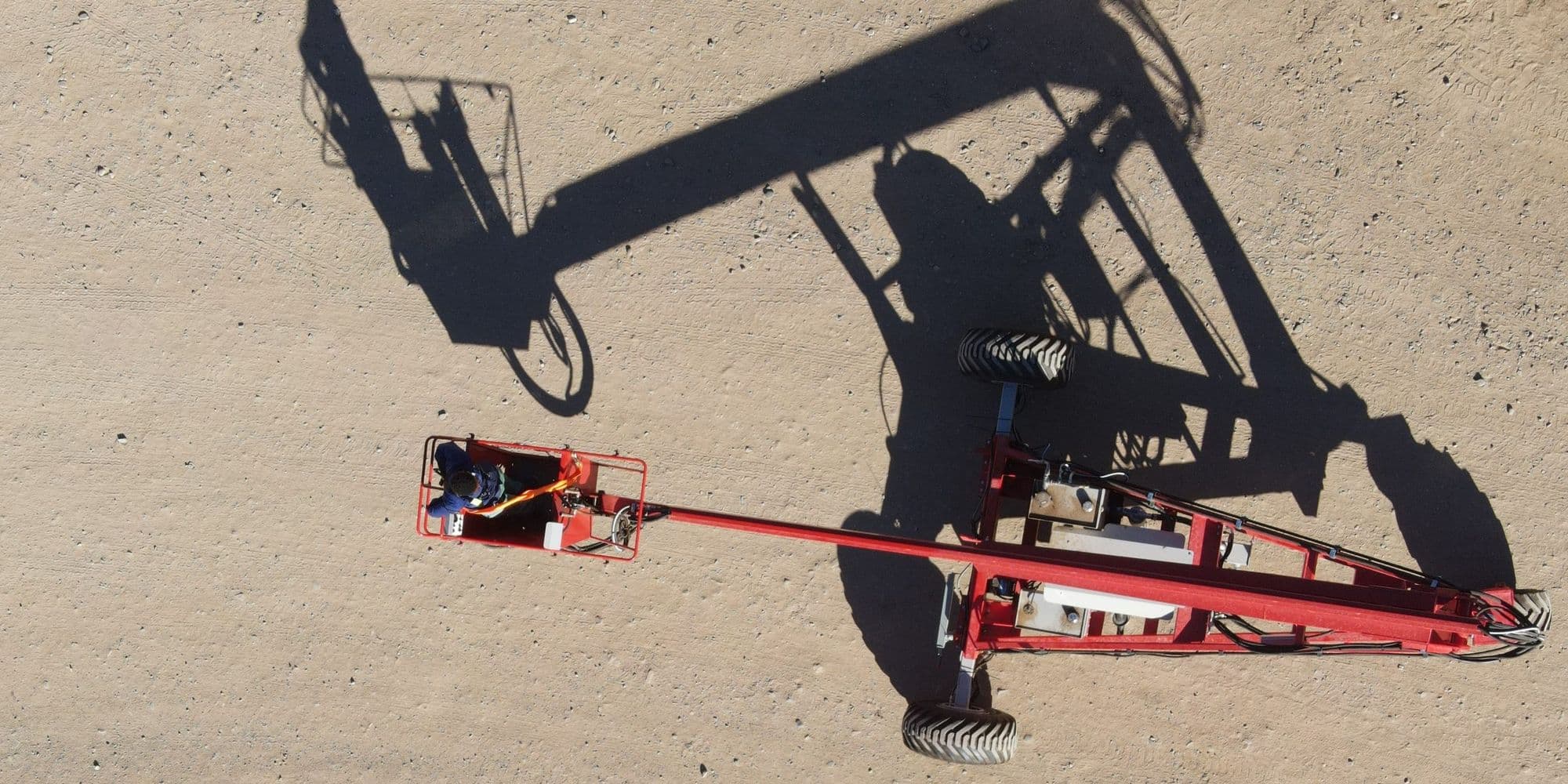 Red Ant pruning tower seen from above, casting a long shadow across the orchard floor